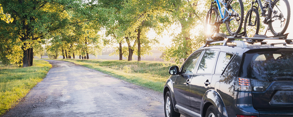 Black SUV parked on a rural road with two bicycles mounted on the roof rack - www.vanpeltinsurance.com