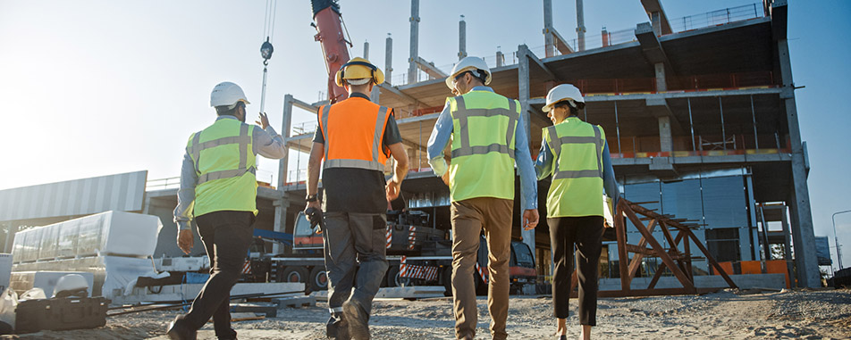 Four construction workers wearing safety helmets and reflective vests - www.vanpeltinsurance.com